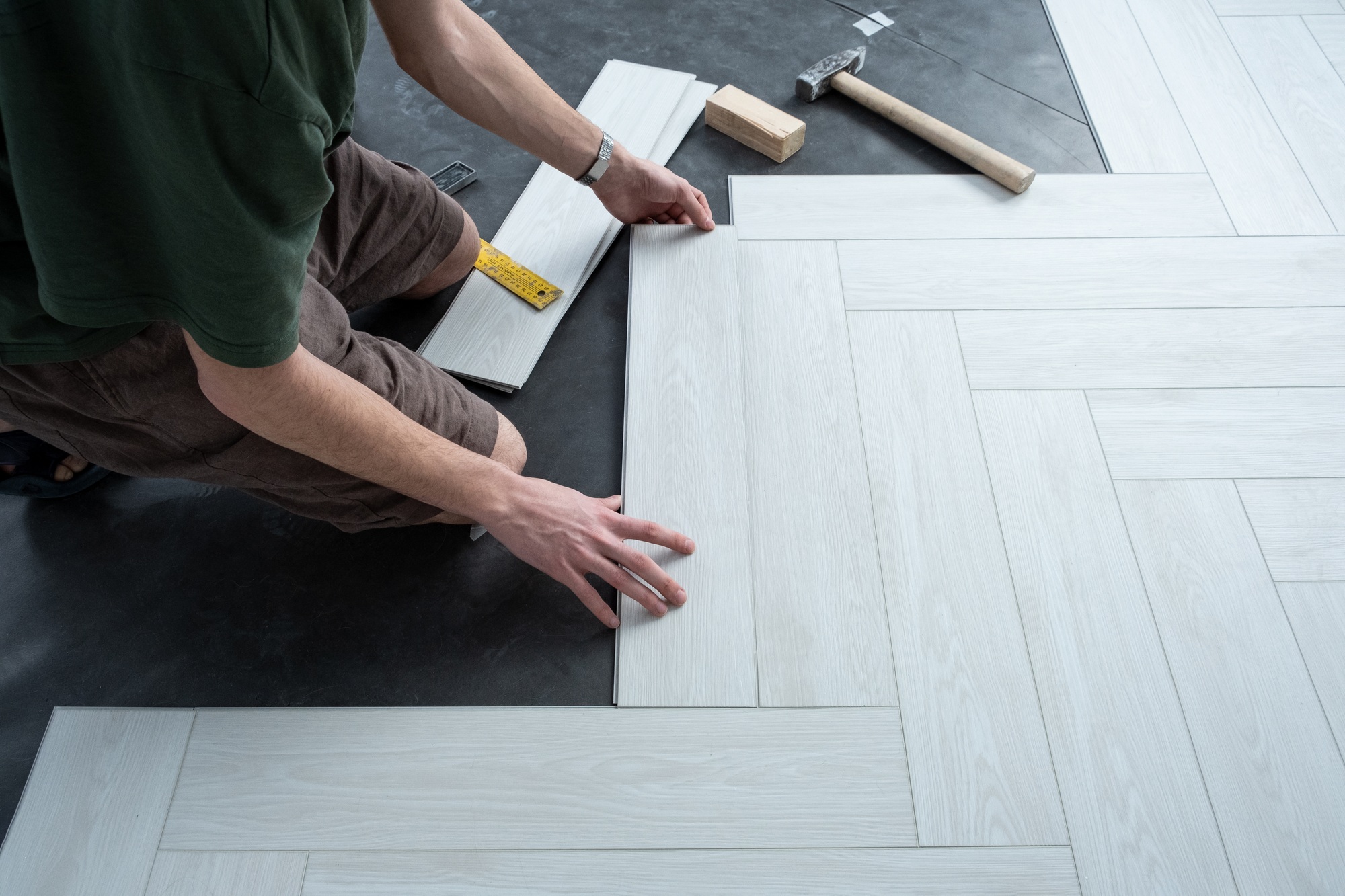 A man lays a quartz laminate on the floor. Renovation, Installation of French herringbone